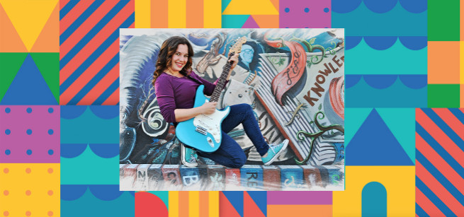 Nathalia playfully holding blue electric guitar