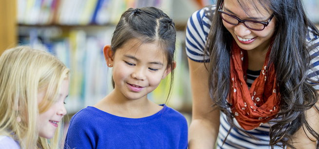 Two children listen to a STAR reader at the library.
