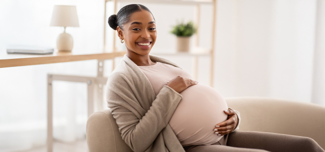 Pregnant woman holding her belly while sitting on a couch