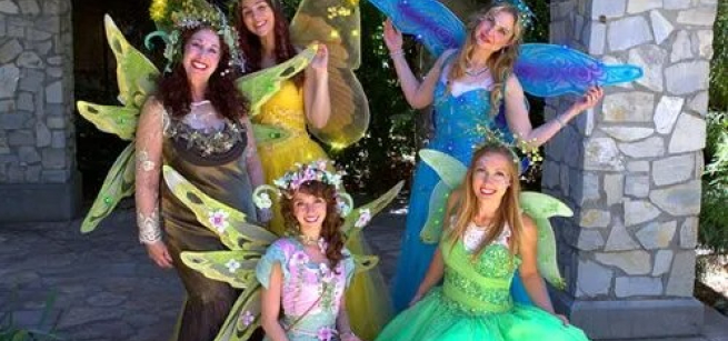 A performance group of five women dressed as colorful fairies. 