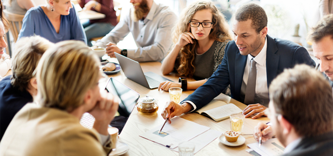 group of people sitting at a table going over documents
