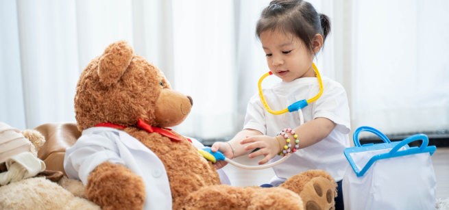 A child plays doctor with a teddy bear