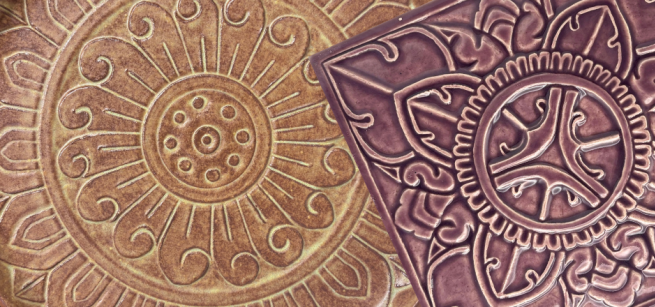 Floral relief on a round, earth-toned ceramic piece and floral relief on a square dark brown ceramic piece.