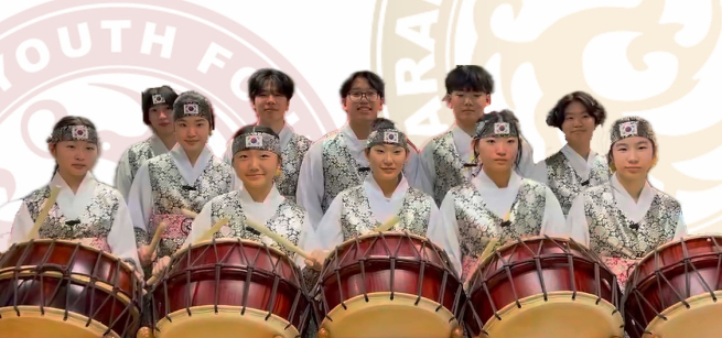 eleven high school students wearing Korean clothing hold drumsticks to play Korean barrel drums known as buk