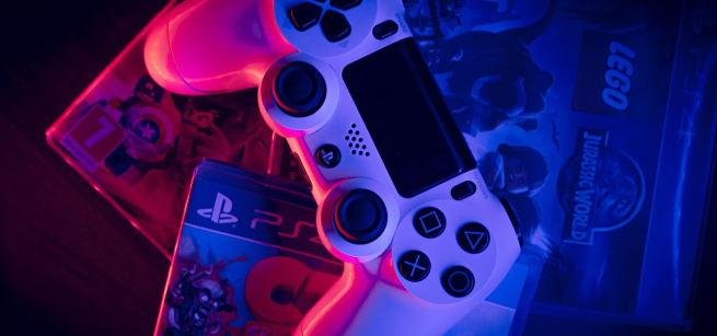 White playstation remote controller on top of video game cases