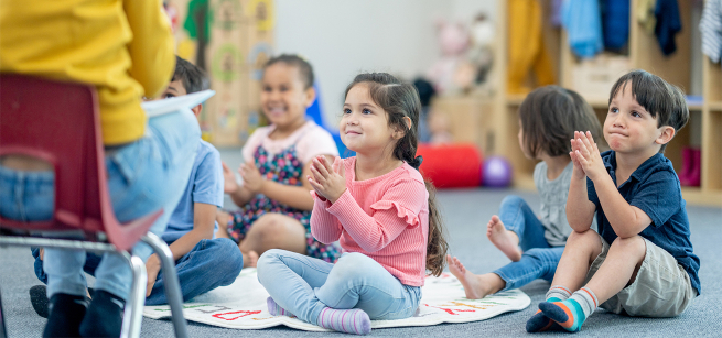 Toddlers seated on the floor listening to a story