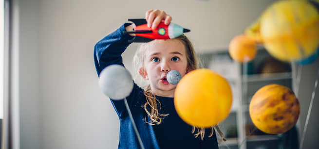 young girl playing with a toy space ship
