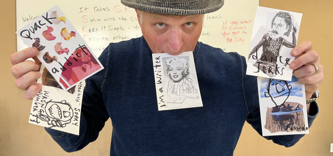A man holds up several examples of completed zines.