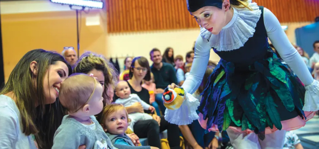 performer interacting with a puppet and a baby and mother