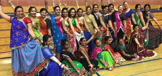 group of dancers dressed in colorful Indian saris pose with arms outstretched