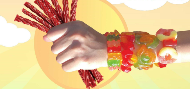 A hand holding red licorice wearing several bracelets made with gummy candies