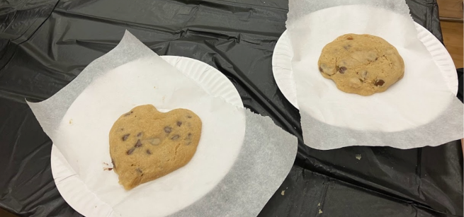 Two Chocolate chip cookies on parchment paper and paper plates