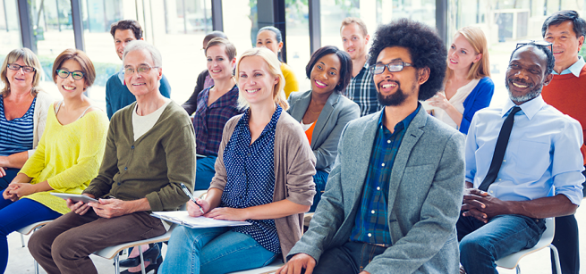 A group of adult learners are engaged and in a classroom. 