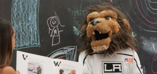 A woman reads a picture book to Bailey the LA Kings mascot.