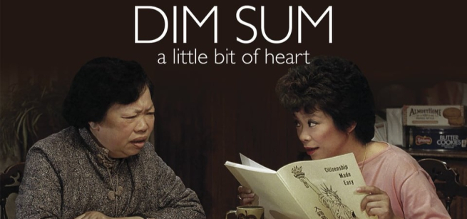 An older and a younger women sit at a table. The younger woman is reading a booklet titled Citizenship Made Easy.