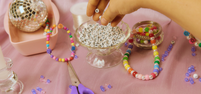a bowl full of letter beads and friendship bracelets on a table