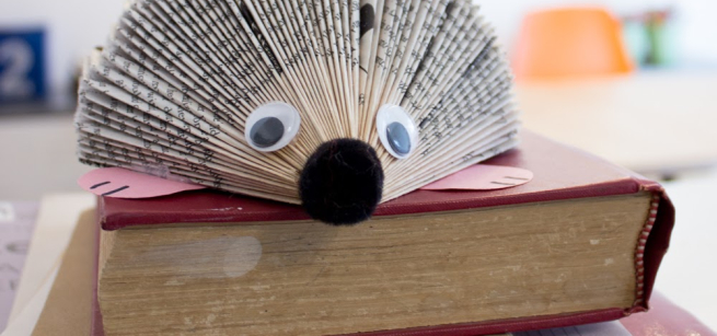 a folded book hedgehog sits on top of an old book