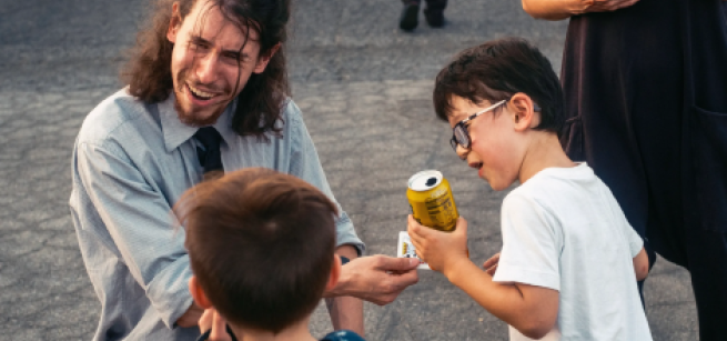 A magician showing two children a magic trick.