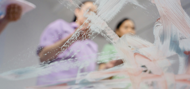 women painting through glass