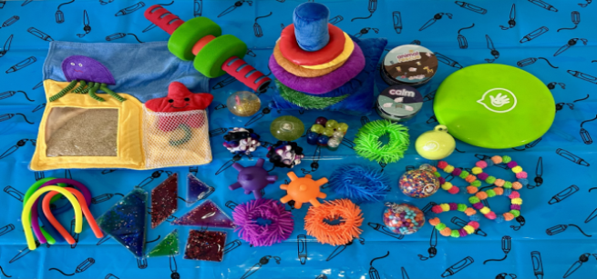 On a blue background are sensory toys such as fidgets, squishy balls, and tangram gel puzzles.
