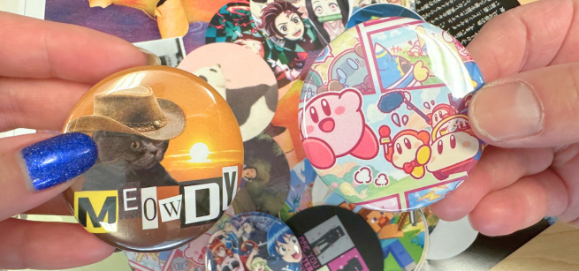 Two hands display handmade pin buttons.