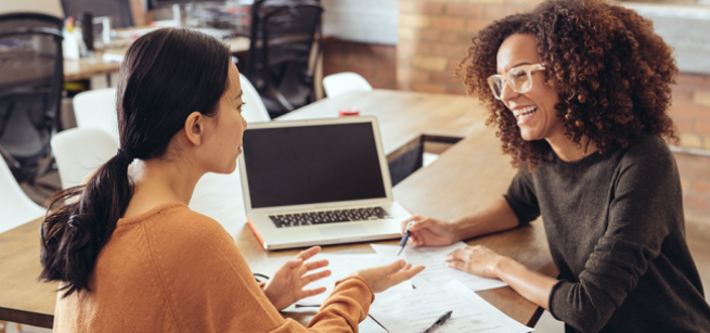 two people talking with paperwork and laptop