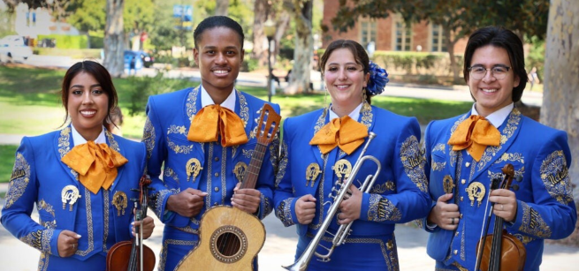 Three females and one male students with music instruments and wearing vibrant blue mariachi outfits.