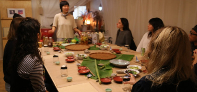 woman standing at the end of a table talking to a table full of people