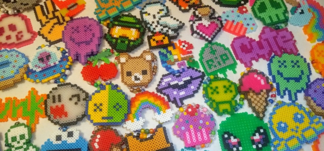 An assortment colorful Perler bead creations scattered across a white table.