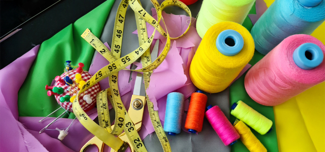 spools of thread, measuring tape, colorful fabric, scissors and pin cushion