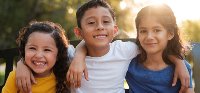 Three children with arms around each other's shoulders