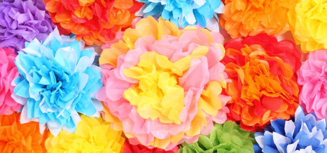 Brightly colored tissue paper flowers in various shades of pink, blue, yellow, orange, and purple fill the frame, creating a vibrant and cheerful display.