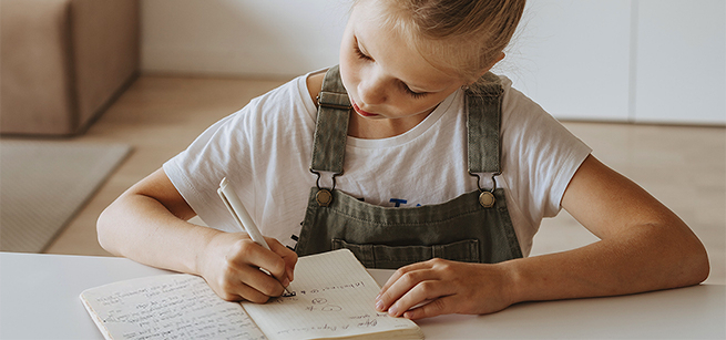 Young girl writing in a journal.