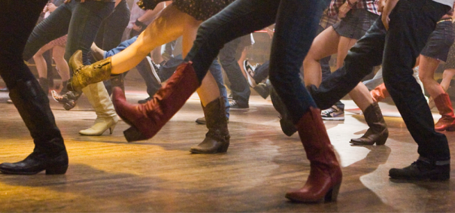 a photo of a group of people line dancing showing legs and feet only