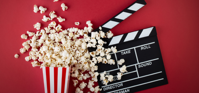 Popcorn and a clapper board on the red background