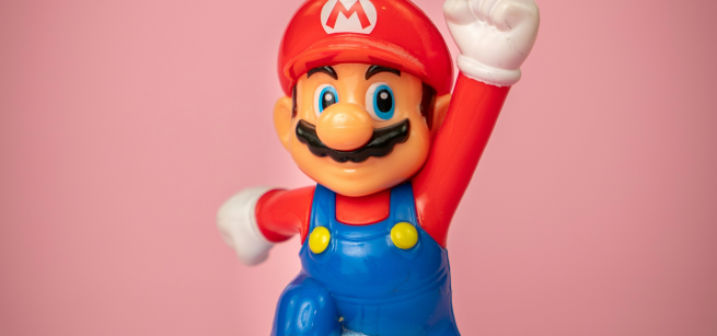 Super Mario jumping in front of a pink background with his first up