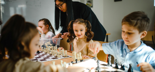 girls and boy playing chess