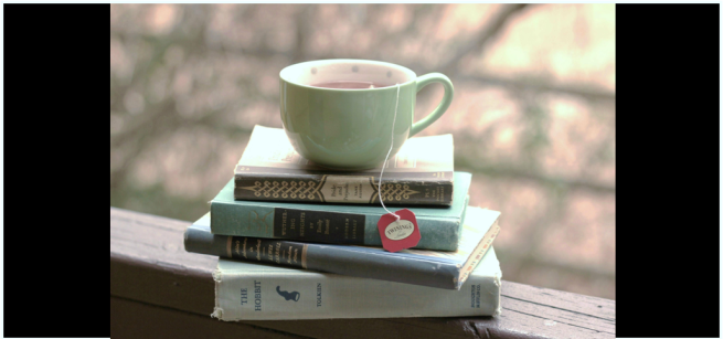 Photo of a cup of tea on a pile of books outside.