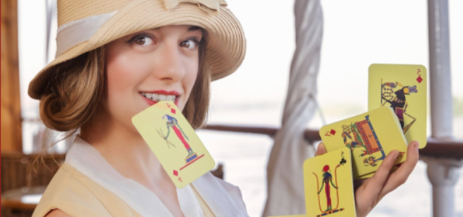 Katrina holding one playing card in her teeth and a bridge spread of other cards between two hands