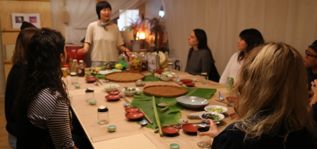 Chef Jess Wang speaking to people at the dinner table. 