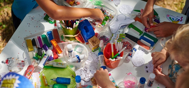 Children create art at a table with paints and brushes