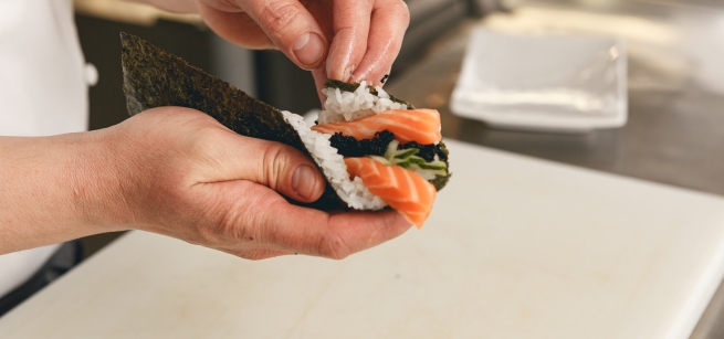 chef hands cooking sushi with rice salmon and nori