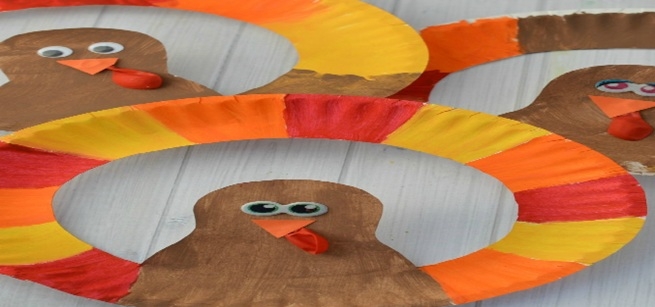 Paper plate with alternating red, yellow, orange colors and a cut out of a brown colored turkey.