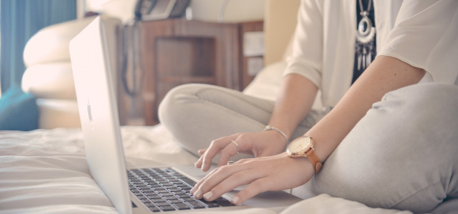 student sitting and typing on a laptop