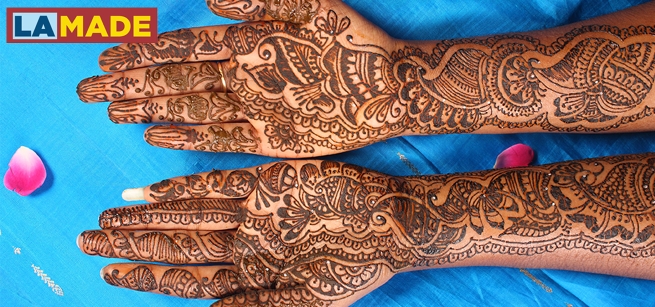 Two outstretched arms covered in black henna tattoos