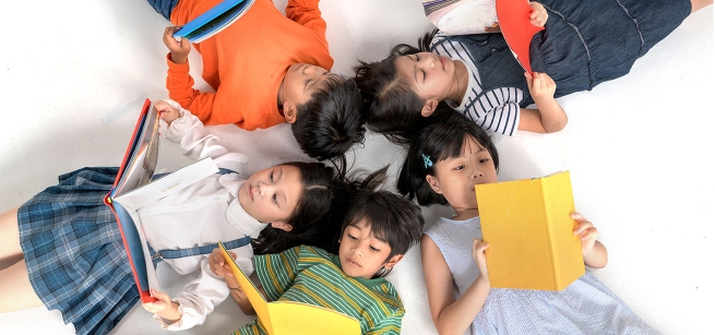 kids laying on the ground in a circle each reading a book