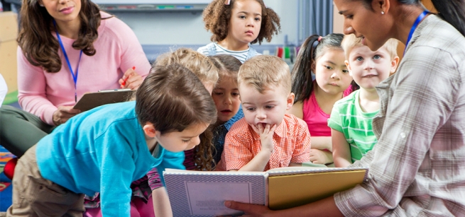 children looking at a book being read to by a librarian