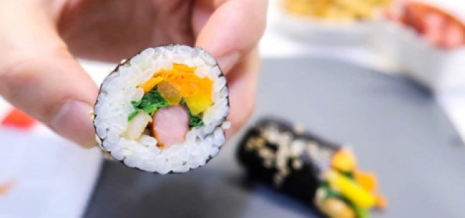 hand holding a slice of Korean kimbap roll