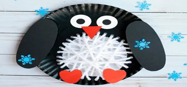 Paper plate craft colored black in the style of a penguin with a white center