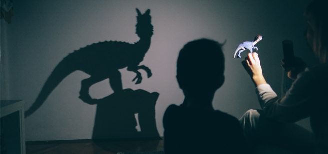 Young people project a raptor shadow on the wall